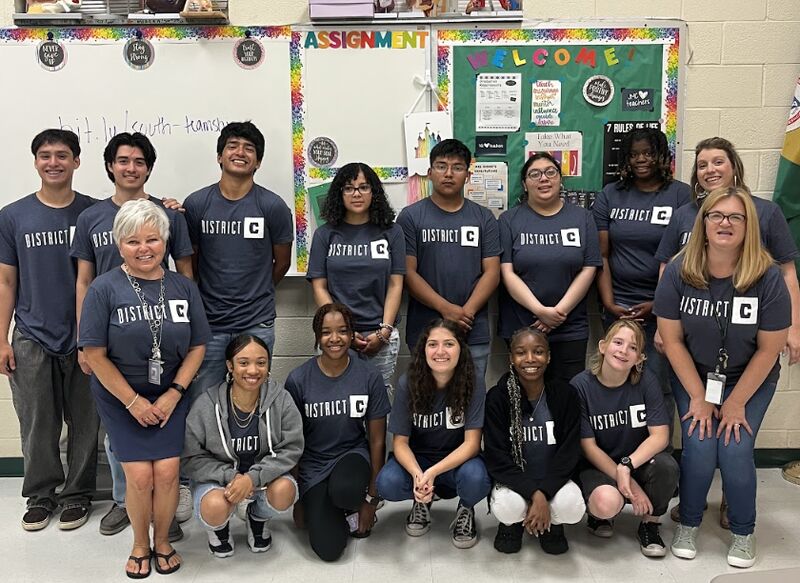 Teachers and students together in front of a white board.